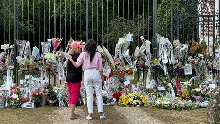 Anouchka Delon (à droite), se tient devant des dizaines de bouquets de fleurs déposés à l'entrée de la propriété de son père Alain Delon à Douchy (Loiret), le 21 août 2024. (TOM MASSON / AFP)