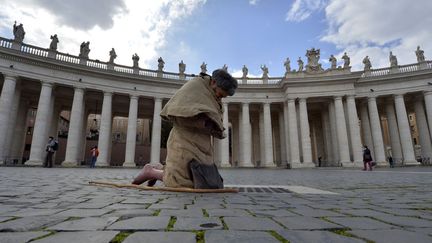 Un homme pieds nus prie sur la place Saint-Pierre au Vatican, le 12 mars 2013. (ANDREAS SOLARO / AFP)