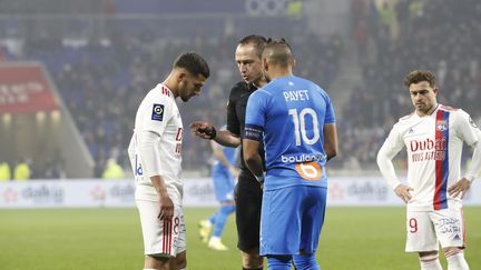 L'arbitre du match OL-OM Ruddy Buquet réunit les deux capitaines, Houssem Aouar et Dimitri Payet, lors du début des incidents le 21 novembre 2021. (SPEICH FREDERIC / MAXPPP)