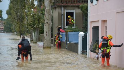 Des secouristes portent assistance à des personnes bloquées chez elles, le 15 octobre 2018, à Trèbes (Aude). (PASCAL PAVANI / AFP)