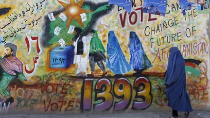 Une femme afghane passe devant un mur recouvert de graffiti appelant &agrave; voter lors des &eacute;lections pr&eacute;sidentielles qui se d&eacute;rouleront le 5 avril prochain, province de Kandahar (Afghanistan), le 30 mars 2014. (AHMAD NADEEM / REUTERS)