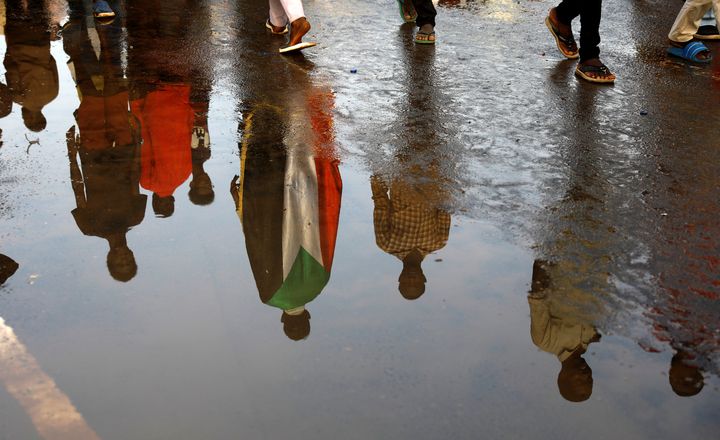 Manifestants soudanais, reflétés dans une flaque d'eau, devant le ministère de la Défense à Khartoum (capitale du Soudan) le 17 avril 2019 (Reuters - UMIT BEKTAS / X90076)