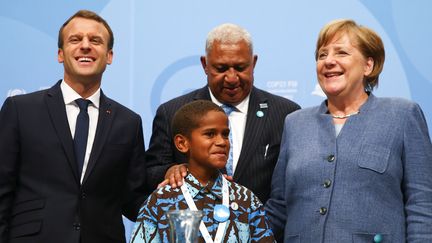 Le président français Emmanuel Macron, le premier Ministre fidjien&nbsp;Frank Bainimarama, la chancelière allemande Angela Merkel et le fidjien Timothy Naulusala, réfugié climatique, le 15 novembre 2017 à Bonn, en Allemagne, pour la COP23.&nbsp; (WOLFGANG RATTAY / REUTERS)