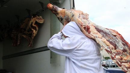 Un employ&eacute; r&eacute;quisitionn&eacute; transporte des morceaux de viande suspecte, le 16 d&eacute;cembre 2013, &agrave; Narbonne (Aude). (RAYMOND ROIG / AFP)