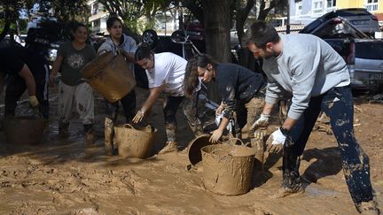 A Massanassa, un village de 9 000 habitants, des volontaires organisent une chaîne humaine pour enlever la boue à l'aide de seaux. (JOSE JORDAN / AFP)