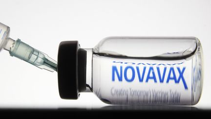 Une seringue et une fiole devant le logo du laboratoire Novavax, le 24 novembre 2020. (STR / NURPHOTO / AFP)