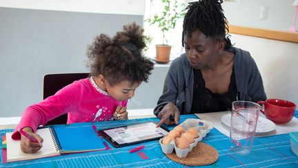 Une mère confinée avec sa fille lui apprend une recette de cuisine, le 25 mars 2020 à&nbsp;Grézieu-la-Varenne (Rhône). (SEBASTIEN RIEUSSEC / HANS LUCAS / AFP)