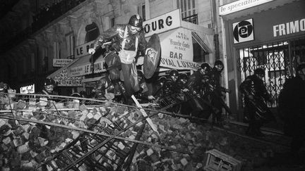 Des CRS franchissent une barricade, rue Gay-Lussac à Paris, dans la nuit du 10 au 11 mai 1968. (SIPA)