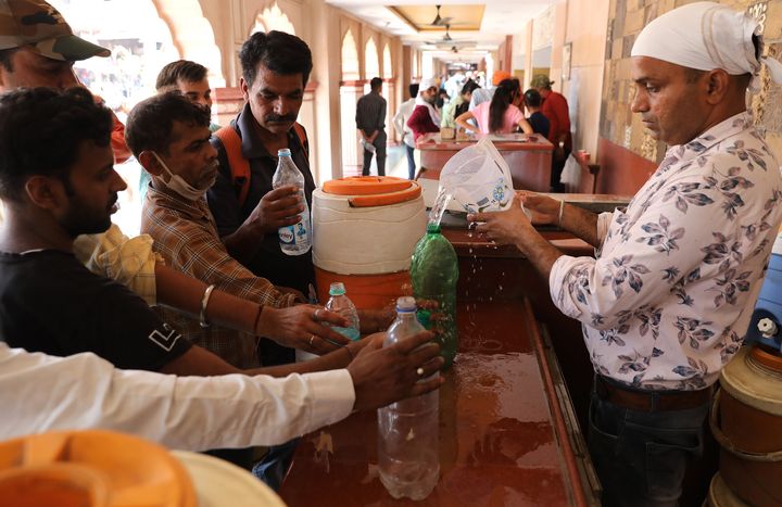 Un volontaire distribue gratuitement de l'eau potable à l'extérieur d'un temple dans les vieux quartiers de Delhi, en Inde, le 13 mai 2022. (RAJAT GUPTA / EPA / MAXPPP)