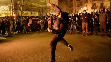 Un manifestant lance un pavé sur les forces de police catalanes à Barcelone ce vendredi 18 février 2021. L'emprisonnement du rapper Pablo Hasél a déclenché des affrontements depuis le 16 février.&nbsp; (JOSEP LAGO / AFP)