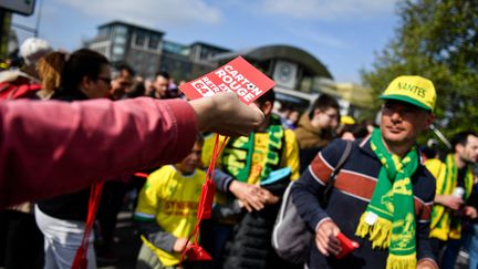 Un syndicaliste distribue des cartons rouges avant la finale de la Coupe de France opposant Nantes et Toulouse le 30 avril 2023. (JULIEN DE ROSA / AFP)