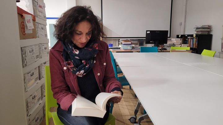 La directrice littéraire du salon du livre et de la presse jeunesse de Montreuil, Nathalie Donikian, feuillette Oxcean, aux éditions Talents Hauts, en lice pour obtenir un prix au salon. (THOMAS GIRAUDEAU / RADIO FRANCE)