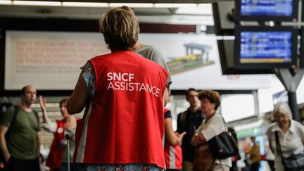 Un personnel de la SNCF aide un client à la gare Montparnasse à Paris, le 30 juillet 2018. (THOMAS SAMSON / AFP)