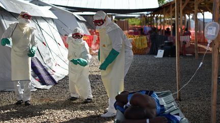 Les agents de sant&eacute; portant des tenues protection dansent devant des malades d'Ebola, dans le centre de traitement de Kenama,&nbsp;g&eacute;r&eacute; par la Croix-Rouge, le 15 novembre 2014. (FRANCISCO LEONG / AFP)