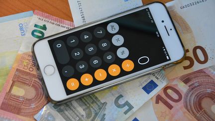 Des billets de 5, 10, 20 et 50 euros et une calculatrice sur un smartphone. (JEAN-CHRISTOPHE BOURDILLAT / FRANCEINFO / RADIO FRANCE)