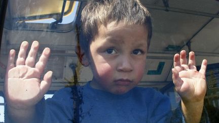 Un jeune Rom regarde &agrave; travers la fen&ecirc;tre du bus qui l'&eacute;vacue de son campement &agrave; Belgrade (Serbie), le 26 avril 2012. (IVAN MILUTINOVIC / REUTERS)