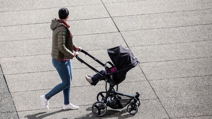 Une personne déplace dans la rue une poussette avec un enfant dedans. (CHRISTOPHE MORIN / MAXPPP)