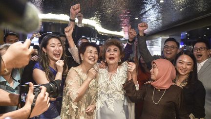 Janet Yeoh (centre R), mère de l'actrice Michelle Yeoh, Oscar de la meilleure actrice dans un rôle principal, célèbre l'événement dans un cinéma de  Kuala Lumpur, où la 95e cérémonie des Oscars à Los Angeles était retransmise en direct, le 13 mars 2023 (ARIF KARTONO / AFP)