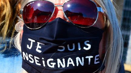 Une femme porte un masque sur lequel il est écrit "Je suis enseignante", lors d'un rassemblement à Bordeaux en hommage à Samuel Paty, le 18 octobre 2020. (MEHDI FEDOUACH / AFP)