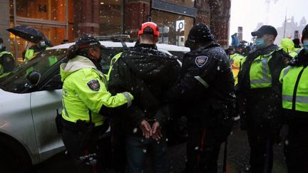 Des policiers escortent un manifestant lors d'une manifestation contre les restrictions sanitaires à Ottawa, au Canada, le 17 février 2022. (DAVE CHAN / AFP)