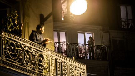 Des Parisiens applaudissent les soignants mobilisés par la lutte contre le Covid-19, le 20 mars 2020 à 20 heures. (MARTIN BUREAU / AFP)