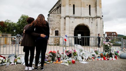 Des anonymes se recueillent devant l'église de Saint-Etienne-du-Rouvray après l'assassinat terroriste du Père Jacques Hamel, le 26 juillet 2016. (CHARLY TRIBALLEAU / AFP)