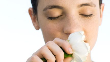 Une jeune femme sent une fleur. Photo d'illustration. (MICHÈLE CONSTANTINI / MAXPPP)