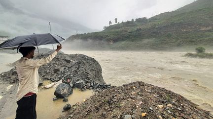 A Rampur, un homme tient fermement son parapluie et assiste à la crue de la rivière Sutlej, provoquée par les pluies de la mousson. Cette ville fait partie de l'Etat indien de l'Himachal Pradesh (nord du pays), lourdement endeuillé par ces inondations record. Le responsable de la gestion des catastrophes de l'Etat a annoncé le 9 juillet 2023 que 700 routes sont bloquées à cause des glissements de terrain. (AFP)