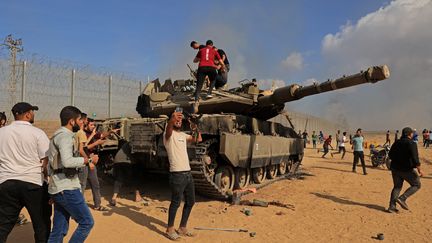 Des Palestiniens prennent le contrôle d'un char de combat israélien Merkava, après avoir traversé la barrière frontalière avec Israël depuis Khan Yunis, dans le sud de la bande de Gaza, le 7 octobre 2023. (SAID KHATIB / AFP)