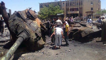 Des habitants de la ville d'Ariha, dans la province d'Idleb, inspectent un blind&eacute; de&nbsp;l'arm&eacute;e syrienne d&eacute;truit, mercredi 7 juin 2012. (SHAAM NEWS NETWORK / AFP)