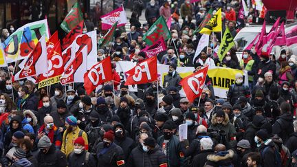 Des manifestants brandissent des drapeaux de syndicats lors d'une mobilisation interprofessionnelle sur les salaires et l'emploi à Paris, le 27 janvier 2022. (THOMAS SAMSON / AFP)