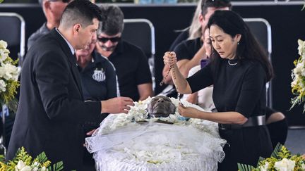 La veuve de Pelé, Marcia Aoki, dépose un rosaire sur le cercueil de son mari. (NELSON ALMEIDA / AFP)