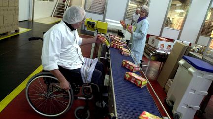 Une personne handicapée travaille sur une chaîne de production dans une entreprise à Houlgate (Calvados). (MYCHELE DANIAU / AFP)