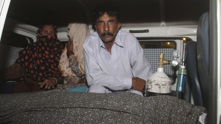 Mohammad Iqbal aux c&ocirc;t&eacute;s de sa femme enceinte lapid&eacute;e &agrave; mort, dans une ambulance, mardi 27 mai &agrave; Lahore (Pakistan). (K.M. CHAUDARY/AP/SIPA / AP)