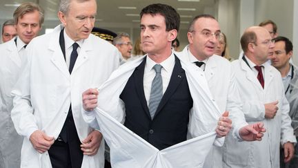 Le Premier ministre Manuel Valls&nbsp;(C) enl&egrave;ve sa blouse &agrave; l'issue de l'inauguration d'une usine de cosm&eacute;tiques&nbsp;Guerlain &agrave; Chartres (Eure-et-Loir), le 6 f&eacute;vrier 2015. (REVELLI-BEAUMONT / SIPA)