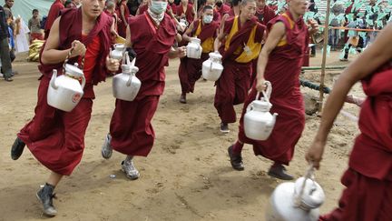 Des moines bouddhistes se ruent avec des th&eacute;i&egrave;res pour assister &agrave; une le&ccedil;on de th&eacute; dispens&eacute;e par le dala&iuml; Lama &agrave; Bodhgaya (Inde), le 2 janvier 2012. (JITENDRA PRAKASH / REUTERS)