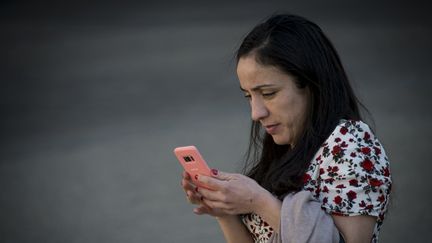 Une femme consulte son smartphone. (MARTIN BERNETTI / AFP)