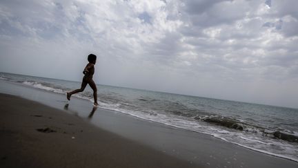 Un enfant court sur une plage d'Ostie, près de Rome, en Italie, le 18 mai 2020. (TIZIANA FABI / AFP)