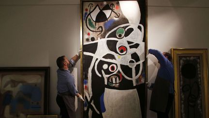 Des employés de Christie's à Londres installent "Femmes et oiseaux" de Miro pour une vente aux enchères qui a finalement été annulée (19 décembre 2013).
