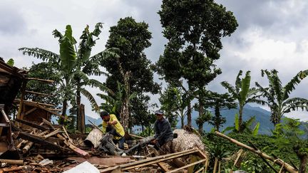 Deux hommes dans des décombres, le 26 novembre 2022 à Java, en Indonésie, cinq jours après un séisme de magnitude 5,6. (GARRY LOTULUNG / NURPHOTO / AFP)