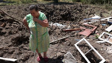 Une femme devant un cratère causé par une frappe devant sa maison à Toretske, dans la région de Donetsk (Ukraine), le 17 juillet 2022.&nbsp; (ANATOLII STEPANOV / AFP)