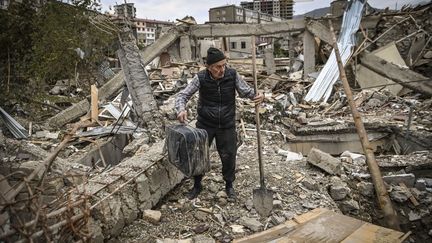 Un policier à la retraite cherche des objets dans les décombres de sa maison, détruite par des bombardements azéris, dans la ville de Stepanakert le 10 octobre 2020. Durant six semaines, Erevan et Bakou se sont affrontés pour se disputer la souveraineté du Haut-Karabakh, enclave peuplée d'Arméniens en Azerbaïdjan.&nbsp;Plus de 5 000 personnes, y compris des civils, ont été tués. Un cessez-le-feu consacrant la défaite arménienne a été signé le 9 novembre. (ARIS MESSINIS / AFP)