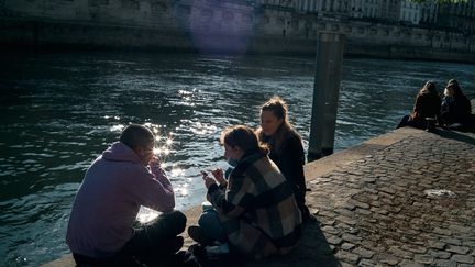 Des jeunes profitent du beau temps sur les quais de Seine à Paris avant le couvre-feu, le 13 avril 2021. (BENOIT DURAND / HANS LUCAS)