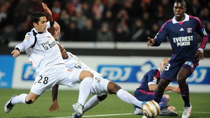 Les Lorientais Gabriel Penalba et Innocent Emeghara &agrave; la lutte avec le Lyonnais Aly Cissokoh (D), le 31 janvier 2012 &agrave; Lorient (Morbihan). (FRANK PERRY / AFP)