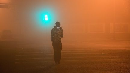 Un piéton se promène, téléphone à la main, dans les rues de Pékin recouvertes d'un nuage de pollution, mardi 20 décembre 2016. &nbsp; (WU HANREN / IMAGINECHINA)