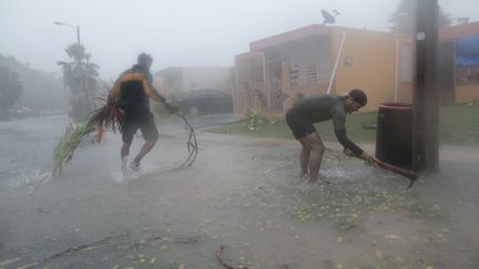 Des habitants ramassent des débris dans la ville de Fajardo, sur l'île de Porto Rico, le 6 septembre 2017. (ALVIN BAEZ / REUTERS)