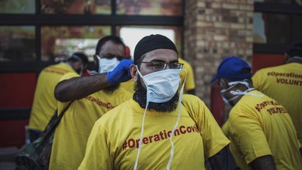 Des bénévoles masqués pour se protéger du coronavirus, dans un township de Johannesburg, le 21 mars 2020. (MARCO LONGARI / AFP)