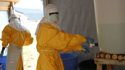 Des soignants se d&eacute;sinfectent apr&egrave;s avoir trait&eacute; des patients porteurs du virus Ebola, &agrave; Lokolia (R&eacute;publique d&eacute;mocratique du Congo), le 5 octobre 2014. (KATHY KATAYI / AFP)