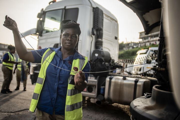 Une des 21 conductrices de camions de Ladybird Logistics vérifie le niveau d'huile de son camion avant le début de la journée de travail à Takoradi, dans l'ouest du Ghana, le 3 avril 2019. (CRISTINA ALDEHUELA / AFP)