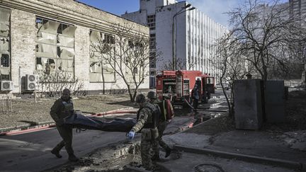 Des membres des services d'urgence militaires ukrainiens retirent le corps d'un militaire ukrainien tué dans une frappe russe, le 22 mars 2022 à Kiev (Ukraine).&nbsp; (ARIS MESSINIS / AFP)